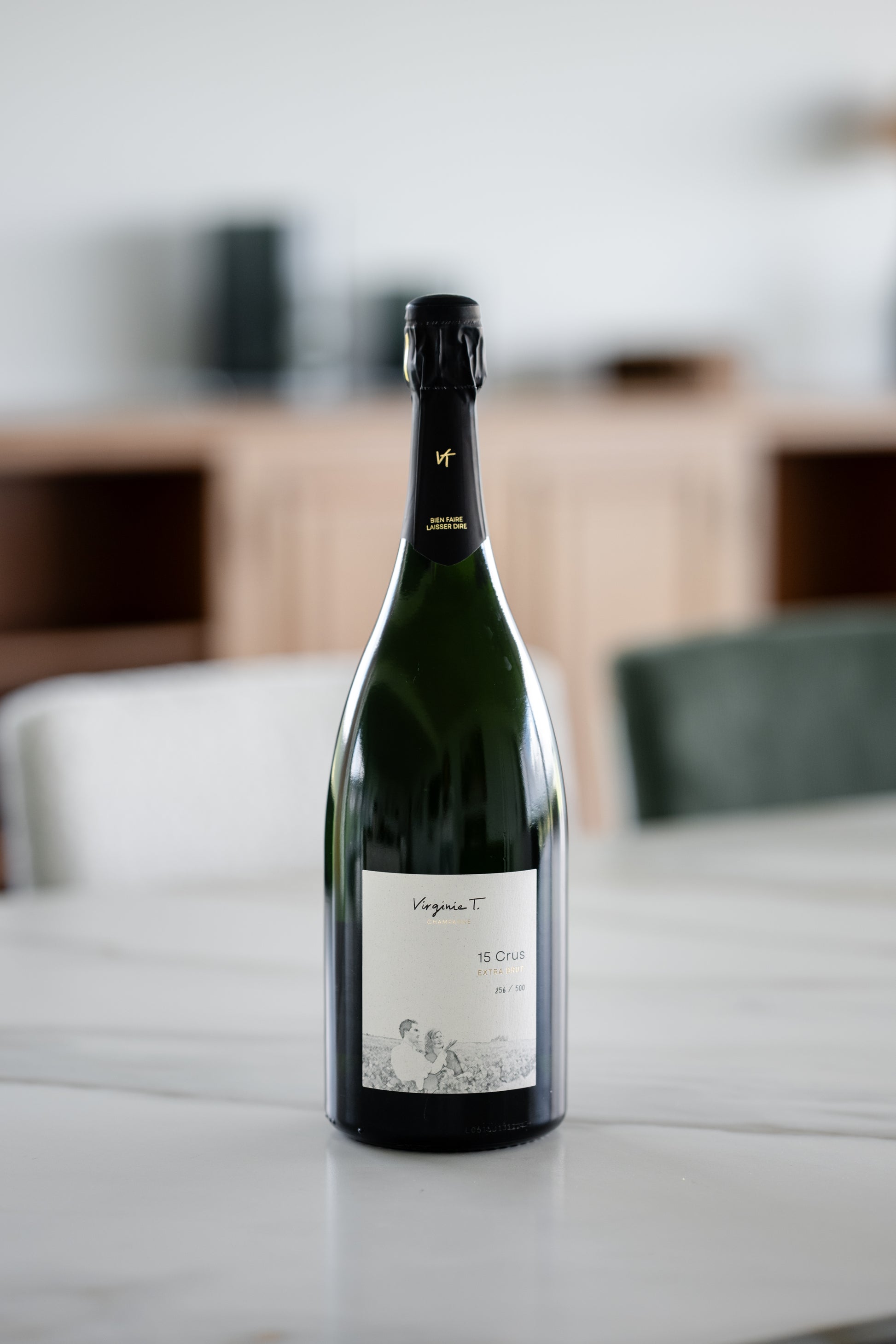 Bouteille de Champagne Virginie T. Blanc de Noirs Grand Cru Extra Brut photographiée sur une table moderne